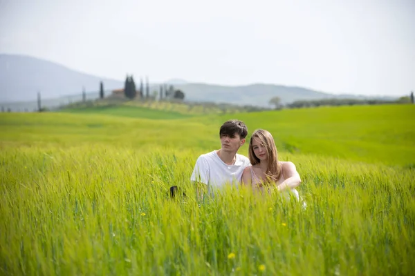 Un jeune couple assis sur une prairie verte — Photo