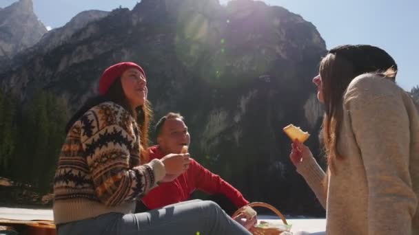 Jovens a viajar. Amigos a fazer piquenique. Sentado na costa e comendo pão — Vídeo de Stock