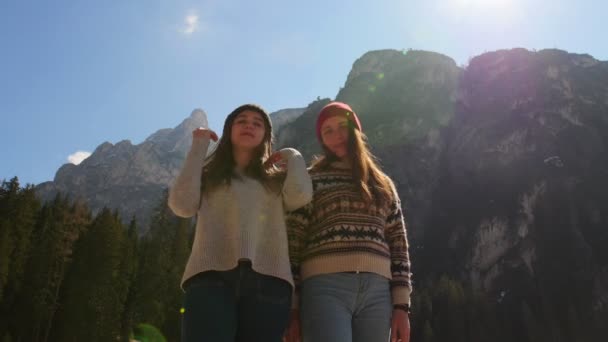 Seyahat eden gençler. İki genç kadın bir dağın arka planında durup poz veriyorlar. — Stok video
