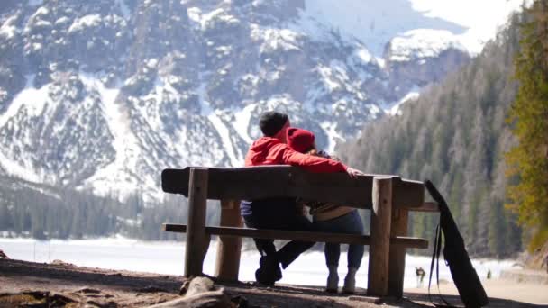 Giovani coppie in viaggio. Seduti su una panchina, abbracciati e goditi la vista — Video Stock