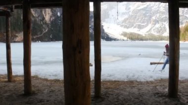 Genç bir kadın büyük bir sırt çantasıyla lago di braies sahilinde yürüyüş yapıyor.