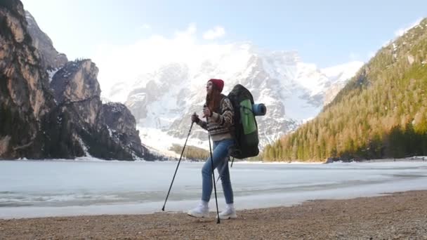 Jovem mulher caminhando em uma costa lago di braies com uma grande mochila itinerante — Vídeo de Stock