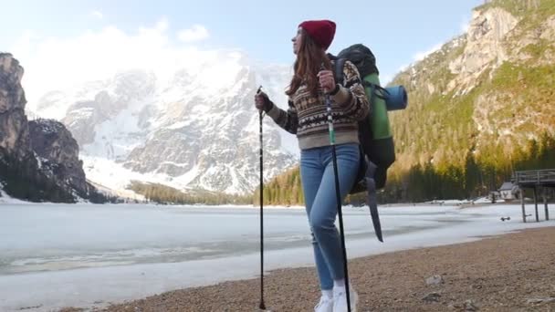 Young woman hiking on a lago di braies coast with a big backpack and looking around — 비디오