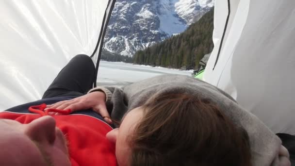 Молодая пара путешествует. Лежат в палатке и обнимаются. — стоковое видео