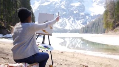 Dolomites. Doğa üzerine bir resim çizen genç bir kadın. Çizim ağaçları ve bir dağ