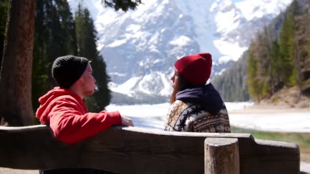 Young couple traveling. Sitting on a bench and talking — Stock Video