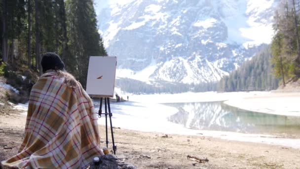 Eine junge Frau sitzt auf dem Stuhl, der mit dem Plaid in den Dolomiten bedeckt ist. Zeichnen eines Gemäldes über die Natur — Stockvideo