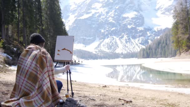 Eine junge Frau sitzt auf dem Stuhl, der mit dem Plaid in den Dolomiten bedeckt ist. Zeichnung eines Gemäldes — Stockvideo