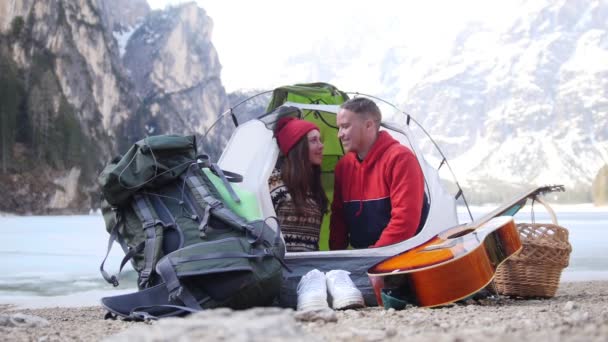 Young couple sitting in the tent. A young woman kiss her boyfriend in the cheek and he winks — 비디오