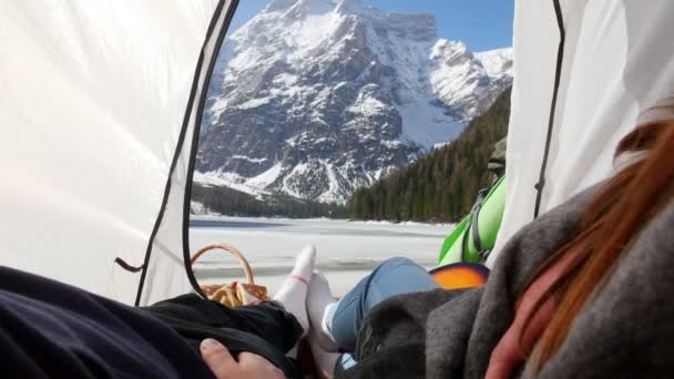 Молодая пара, лежащая в палатке и держащаяся за руки — стоковое видео