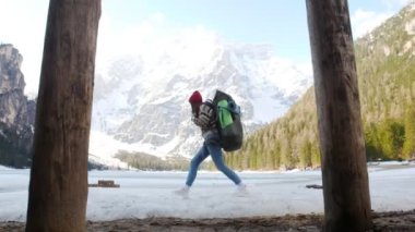 Genç bir kadın büyük bir sırt çantasıyla bir lago di braies sahilinde yürüyor.