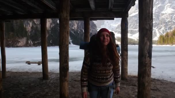 Jonge mooie vrouw wandelen op een lago di braies kust met een grote rugzak — Stockvideo