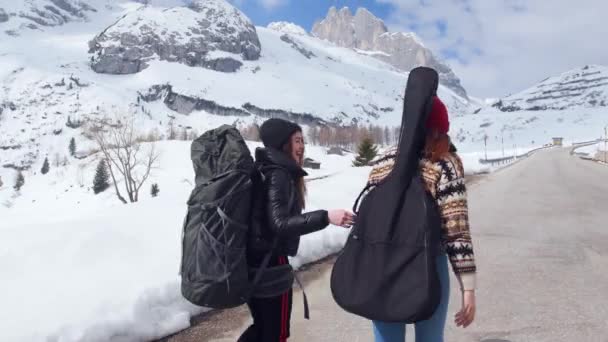 Zwei junge Frauen mit großem Rucksack und Gitarre in den Dolomiten unterwegs — Stockvideo