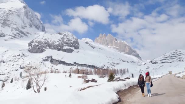 Zwei junge Touristinnen mit großem Rucksack und Gitarre in den Dolomiten unterwegs — Stockvideo