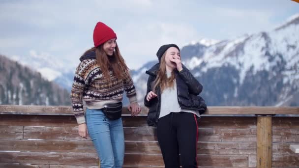 Dos mujeres jóvenes turista de pie sobre un fondo de montañas y riendo — Vídeo de stock