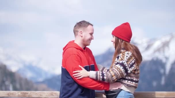 Um jovem casal adorável turistas de pé em um fundo de montanhas e beijo — Vídeo de Stock