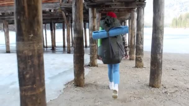 Joven mujer bonita caminando en un lago di braies con una gran mochila — Vídeos de Stock