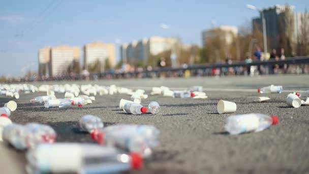 Ein Haufen Plastikbecher und leere Flaschen auf den Straßen während eines Marathonlaufes — Stockvideo