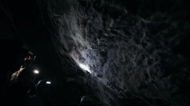 Isliç kayalık bir mağara. İnsanlar minerallerle kaplı mağaranın duvarlarını keşfediyor.