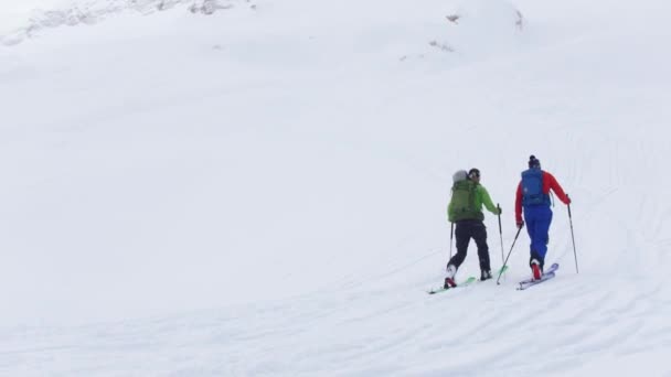 Estación de esquí. Dos personas caminando hacia arriba por el esquí en una montaña — Vídeo de stock