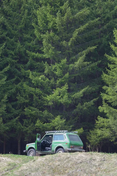 Um jipe em pé na borda do penhasco em um fundo da floresta — Fotografia de Stock