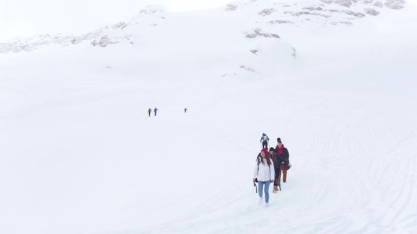 Località sciistica. Giovani amici che camminano sul pendio della neve e si guardano intorno — Video Stock