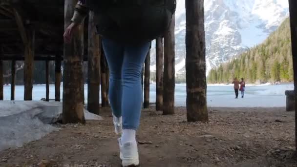 Ung kvinna går på en lago di braies sjö med en stor ryggsäck — Stockvideo