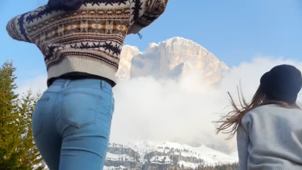 Två resande lyckliga unga kvinnor som springer mot berget och hoppar — Stockvideo