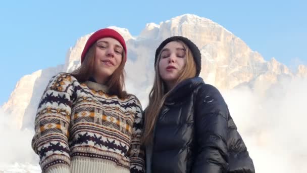 Dos mujeres jóvenes de pie sobre un fondo de una montaña y posando — Vídeo de stock