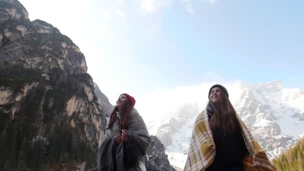 Dos mujeres jóvenes cubiertas de mantas caminando por la costa del lago congelado — Vídeos de Stock