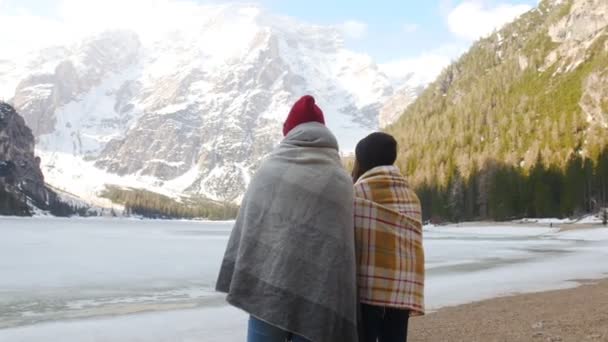 Zwei junge Frauen, die in Decken gehüllt in die Berge blicken — Stockvideo