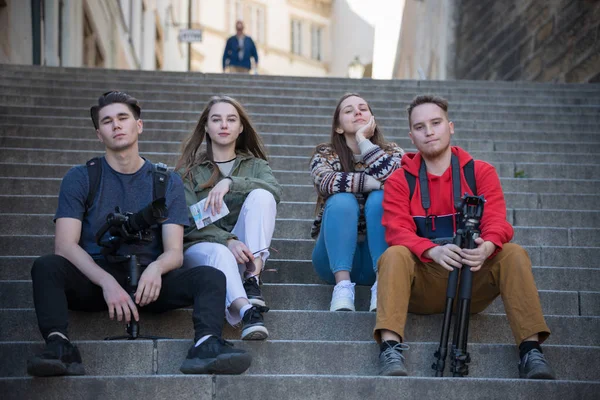 Genç gezgin insanlar merdivenlerde oturuyor. Silahlı adamlar.