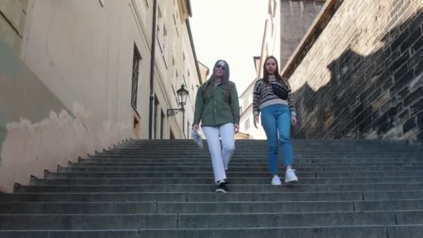 Dua wanita muda berjalan menuruni tangga dan melihat-lihat — Stok Video
