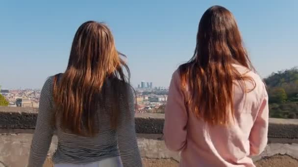 Two young women walks to a border of observation deck and opens up the map — Stock Video