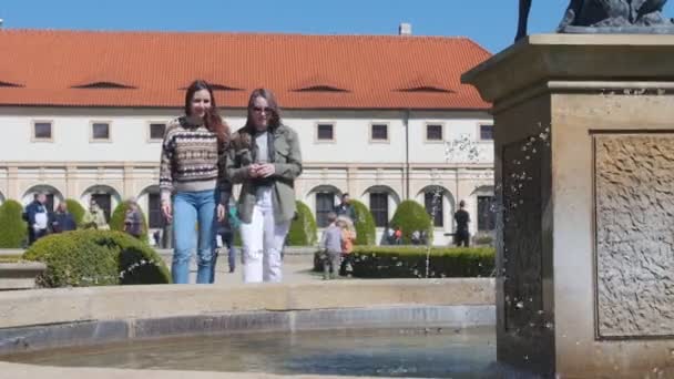 Дві молоді жінки стоять біля фонтану і посміхаються — стокове відео