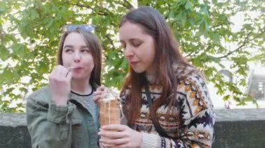 Parkta oturup dondurma yiyen iki genç kadın