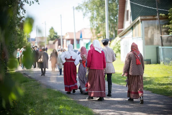 Люди в традиционной русской одежде ходят между деревянными домами — стоковое фото
