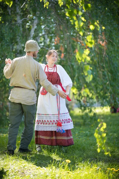 Мужчина и женщина в традиционной русской одежде исполняют русские народные танцы на поле — стоковое фото