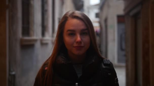 Молодая женщина идет по улице и смотрит вокруг — стоковое видео