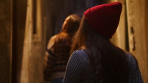 Две напуганные девушки идут по узкой таинственной опасной улице и оглядываются вокруг — стоковое видео