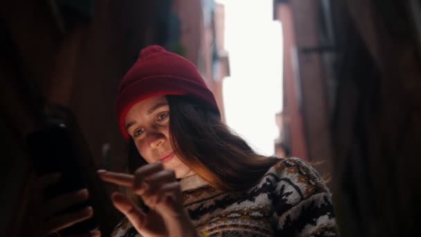 En ung kvinna som står på gatan och tittar på telefonens skärm. Ett ljus lyser upp hennes ansikte — Stockvideo