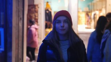 Sokakta yürüyen ve neon Aydınlatma vitrinleri bakarak genç bir kadın