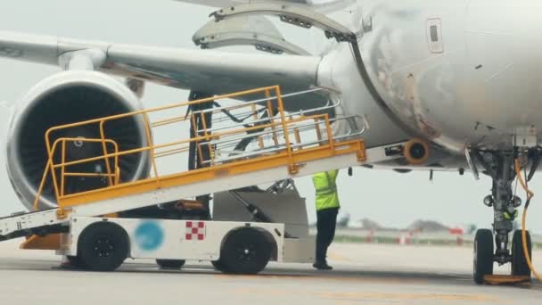 Человек-работник подключает переносной эскалатор для багажа к самолету — стоковое видео