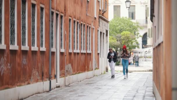 Due giovani donne viaggiano in abiti caldi camminando per le strade strette con un telefono e una macchina fotografica e facendo foto — Video Stock