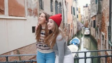 İtalya, Venedik. Su kanalının üzerindeki küçük köprüde duran ve heyecanla etrafa bakan iki genç kadın