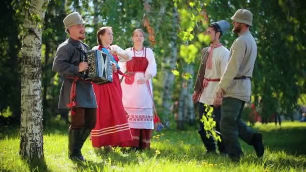 Lidé v tradičních ruských šatech tančí na hřišti-jeden z nich hraje na harmoniku — Stock video