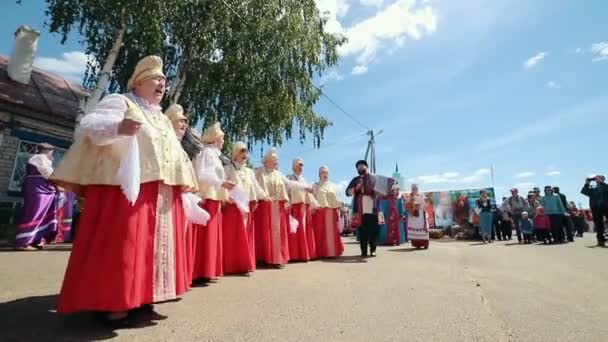 ロシア、ニコルスコエ村、タタールスタン共和国 25-05-2019: 村の道路に立ち、アコーディオン音楽で踊る伝統的なロシアの服を着た老婦人 — ストック動画