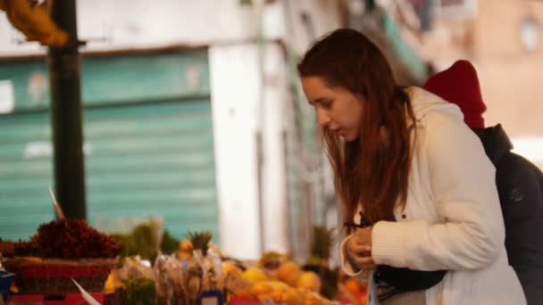 Dos mujeres jóvenes caminando en el mercado exterior y buscando dulces exóticos — Vídeo de stock