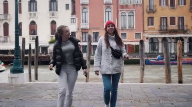 İki genç gülümseyen kadın devam edin ve konuşmak