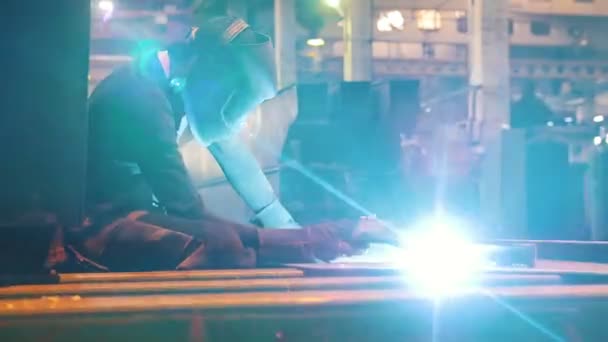 Construcción de plantas. Un hombre sentado en su lugar de trabajo y usando una máquina de soldadura . — Vídeos de Stock